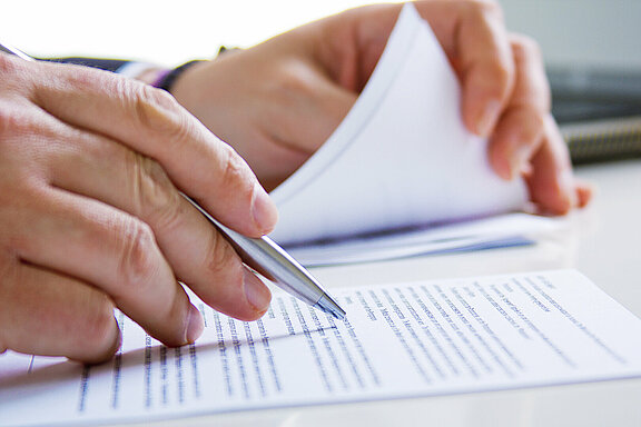 Hands of Business man in dark suit writing in his datebook Zettel_Verordnung_Büro_Hand_Kugelschreiber_lesen_buro-sitzen-notizen-weiss.jpg